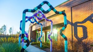 An image of the entrance to the Chatham Park Water Recovery Center with turquoise and purple piping archways leading into a red brick building.