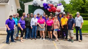 A group of McKim & Creed employees stand outdoors in front of a balloon archway.